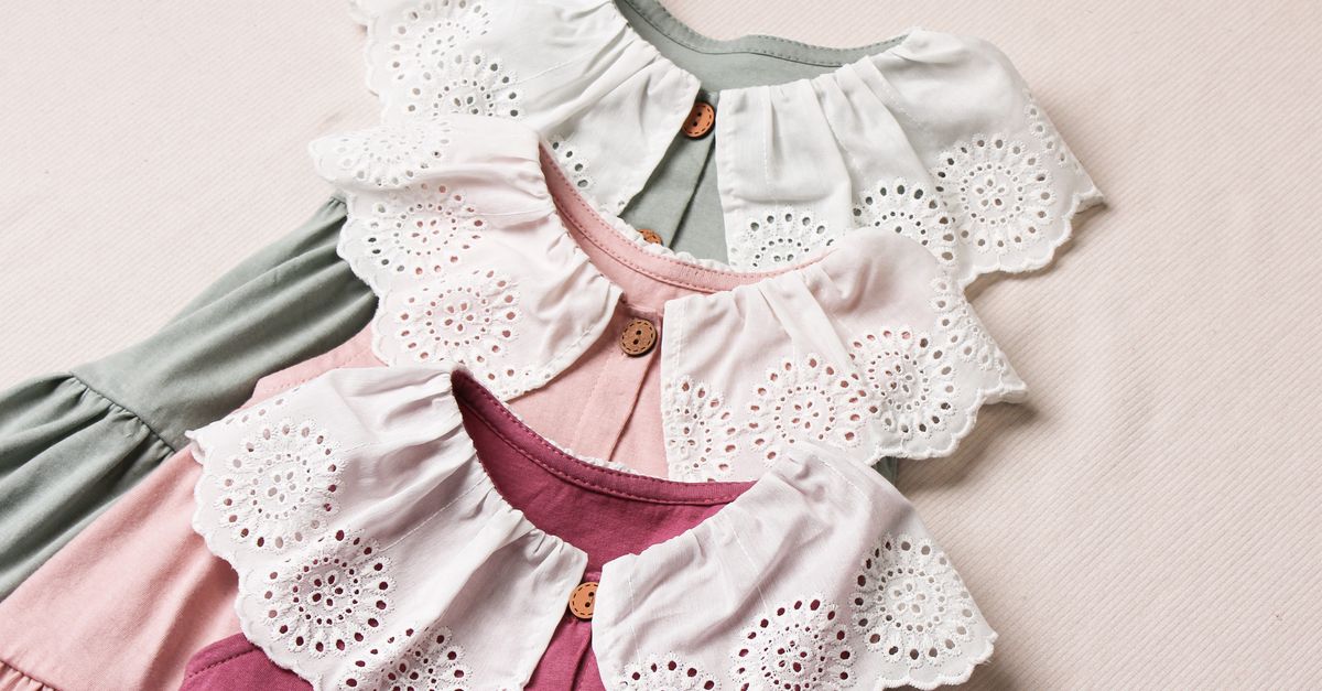 Vestido infantil claro con detalles tejidos colgado sobre una pared de tono neutro