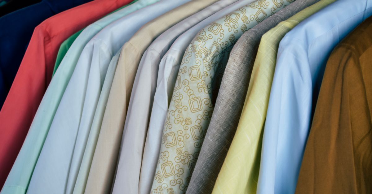 Chaqueta infantil clara colgada junto a una camisa blanca en un perchero de madera